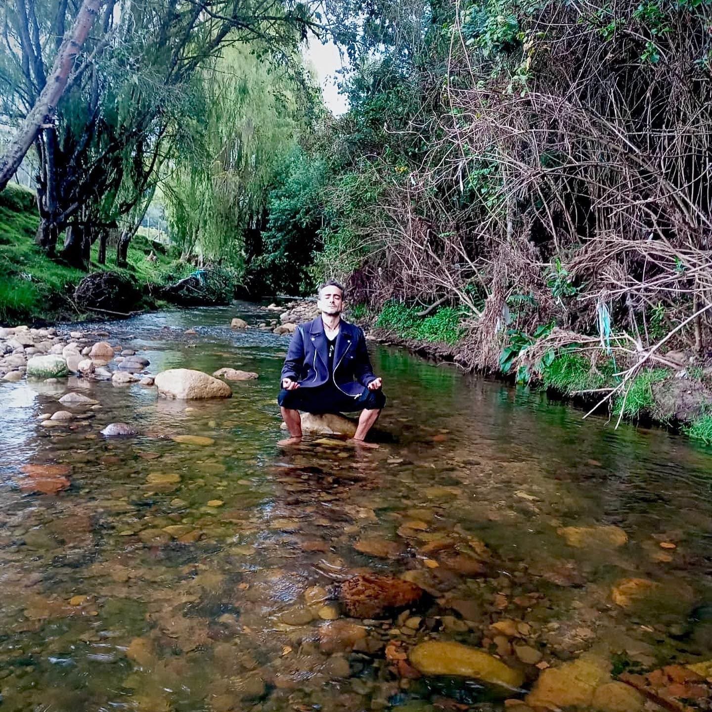El autor sentado en el cauce de un río de aguas claras, entre sauces y piedras.